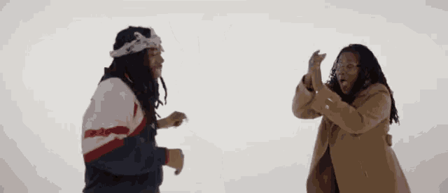 a man and a woman are dancing together in the snow with their arms in the air .