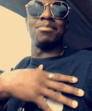 a man wearing sunglasses holds his hand to his heart