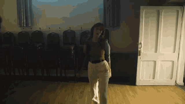 a woman is standing in a room with a door open