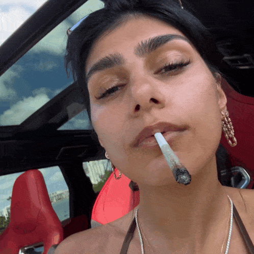 a woman smoking a cigarette in a car with a red seat
