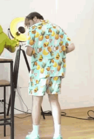 a man wearing a hawaiian shirt and shorts is standing in a room .