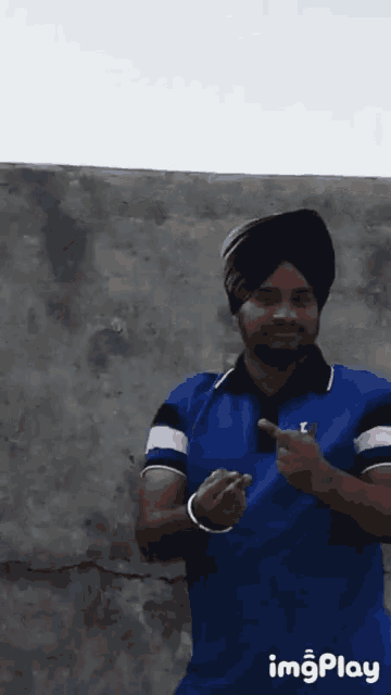 a man wearing a turban and a blue shirt with a l on it