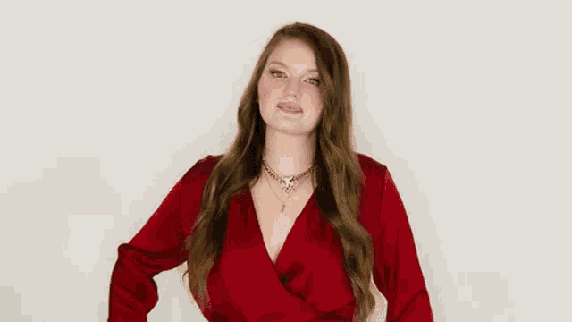 a woman in a red dress is making a funny face and dancing .