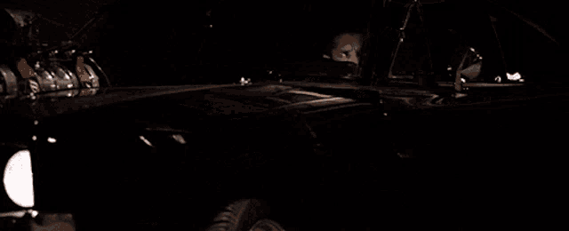 a man in a black leather jacket is standing in a dark room
