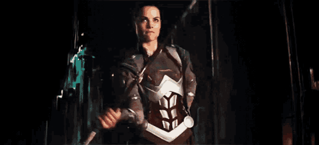 a woman in a superhero costume is holding a sword in her hands .