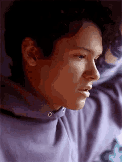a close up of a person 's face wearing a purple hoodie