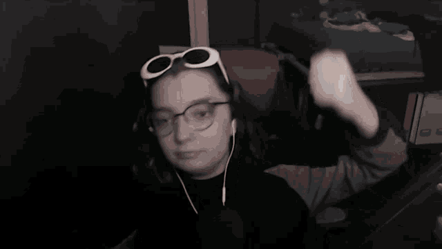 a woman wearing glasses and ear buds is sitting in a chair