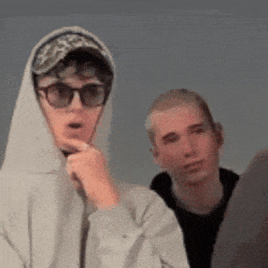 a boy wearing a hoodie and sunglasses looks surprised