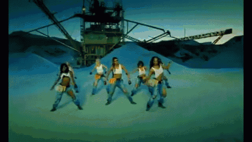 a group of women are dancing in front of a crane that says ' a ' on it