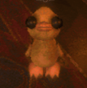 a stuffed animal that looks like a duck with big eyes is sitting on a rug .