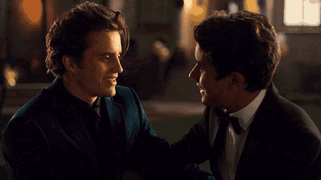 two men in tuxedos are looking into each other 's eyes