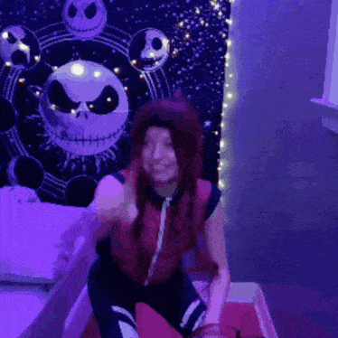 a girl with long red hair is kneeling in front of a nightmare before christmas tapestry