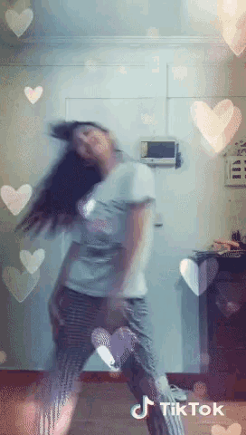 a woman is dancing in a room with hearts around her and a tiktok watermark