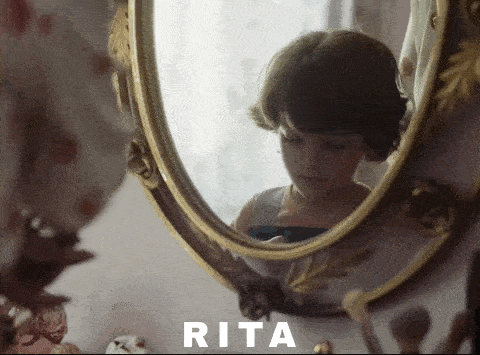 a little girl is looking at herself in a mirror with the name rita written on the bottom