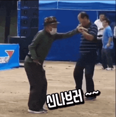 a man wearing a mask is dancing with another man on a dirt field .