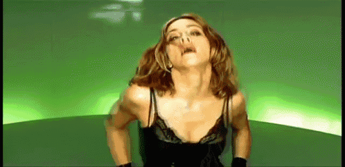 a woman in a black bra is dancing in a green room .