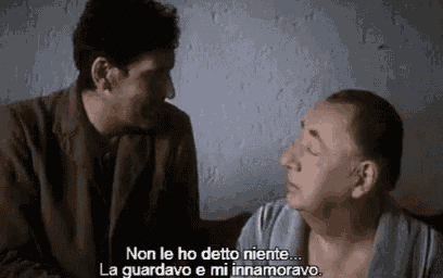 two men are talking to each other in a room with subtitles in italian .