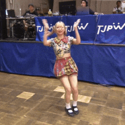 a woman is dancing in front of a blue banner that says tjpw