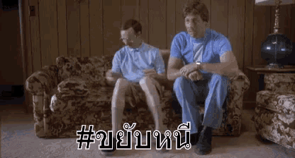 two men are sitting on a couch with their legs crossed in a living room ..