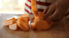a person is cutting a cantaloupe into slices on a cutting board .