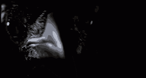 a close up of a person 's face in the dark with a black background .