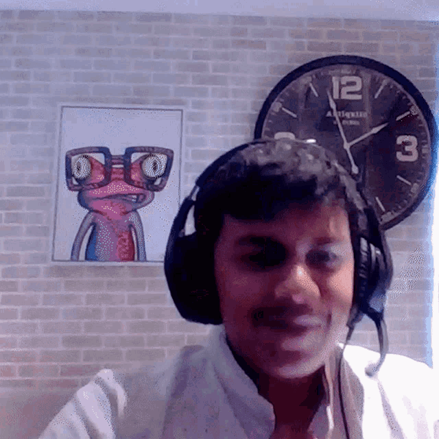 a man wearing headphones stands in front of a clock that says ' antique ' on the face