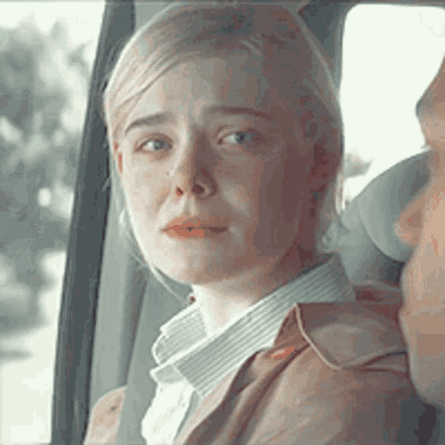 a woman is sitting in the back seat of a car with a man and crying .