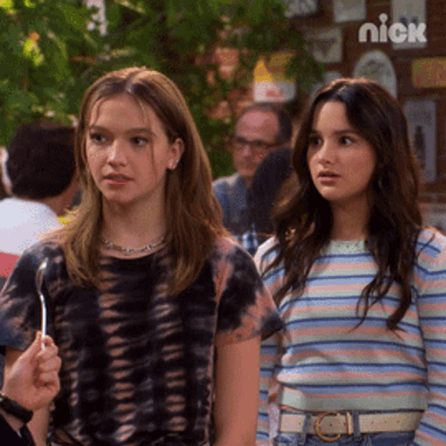 a couple of girls standing next to each other with a nick logo on the bottom right