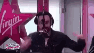 a man is wearing headphones and dancing in front of a virgin logo .