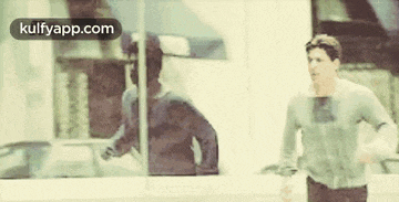a man is running in front of a window with a reflection of him in it .