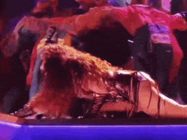 a woman is laying on a stage surrounded by a crowd of people .