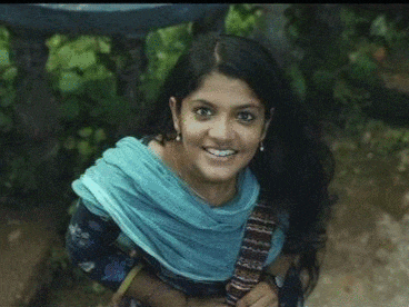 a woman with long hair wearing a blue scarf and earrings smiles for the camera