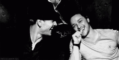 two men are standing next to each other in a dark room and smiling .