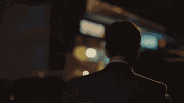 a man in a suit stands in front of a building at night