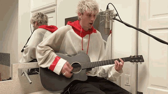 a man playing a guitar in front of a mirror