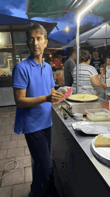a man in a blue shirt is standing in front of a counter with a woman in a striped shirt behind him