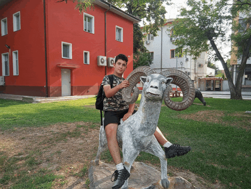 a boy is sitting on a statue of a ram
