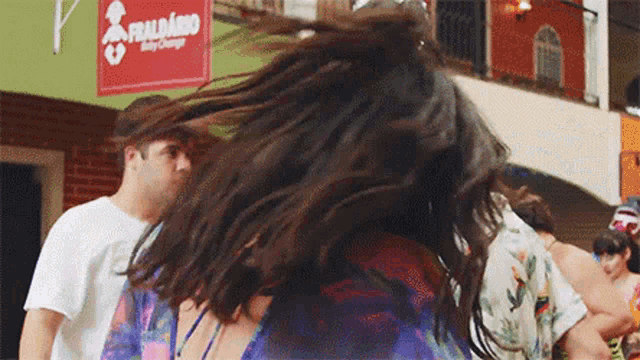 a woman 's hair is blowing in the wind in front of a fraldario sign .