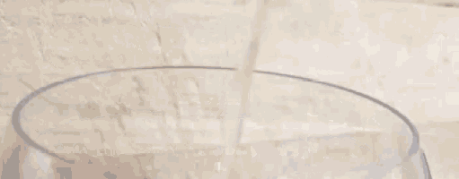 a glass of milk is being poured into a bowl .