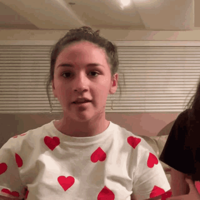 a girl in a white shirt with red hearts on it