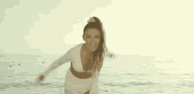 a woman in a white dress is standing in the water with her arms outstretched