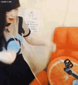 a woman is standing in front of an orange chair with a sign that says honeycam on it