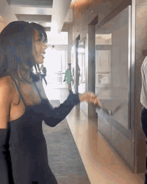 a woman in a black dress stands in a hallway