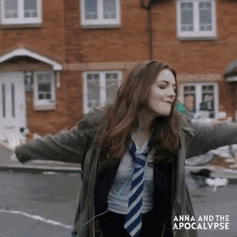 a woman is standing on a street with her arms outstretched and wearing headphones .