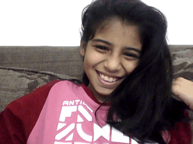 a girl wearing a pink shirt that says " anti " on it