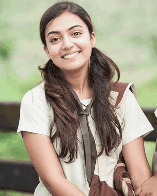 a girl in a white shirt and brown tie smiles