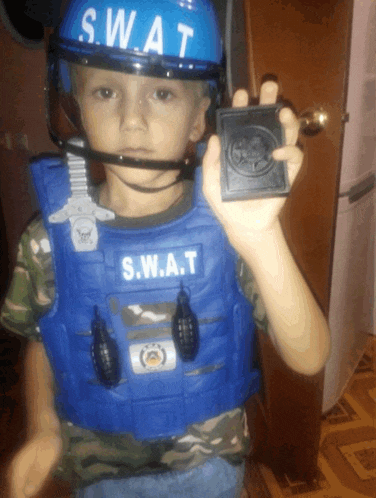 a young boy wearing a s.w.a.t costume and helmet