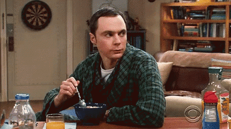 a man is sitting at a table with a bowl of cereal and a spoon .