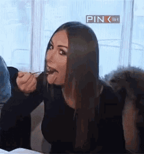 a woman with long hair is sticking her tongue out while eating something