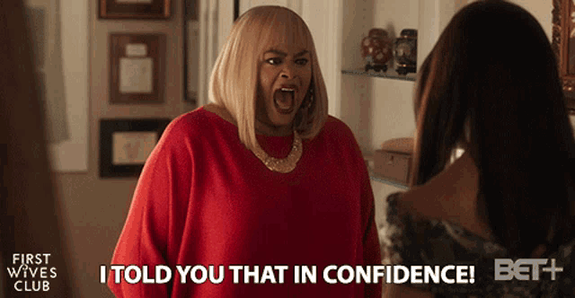 a woman in a red shirt is yelling at another woman and says i told you that in confidence